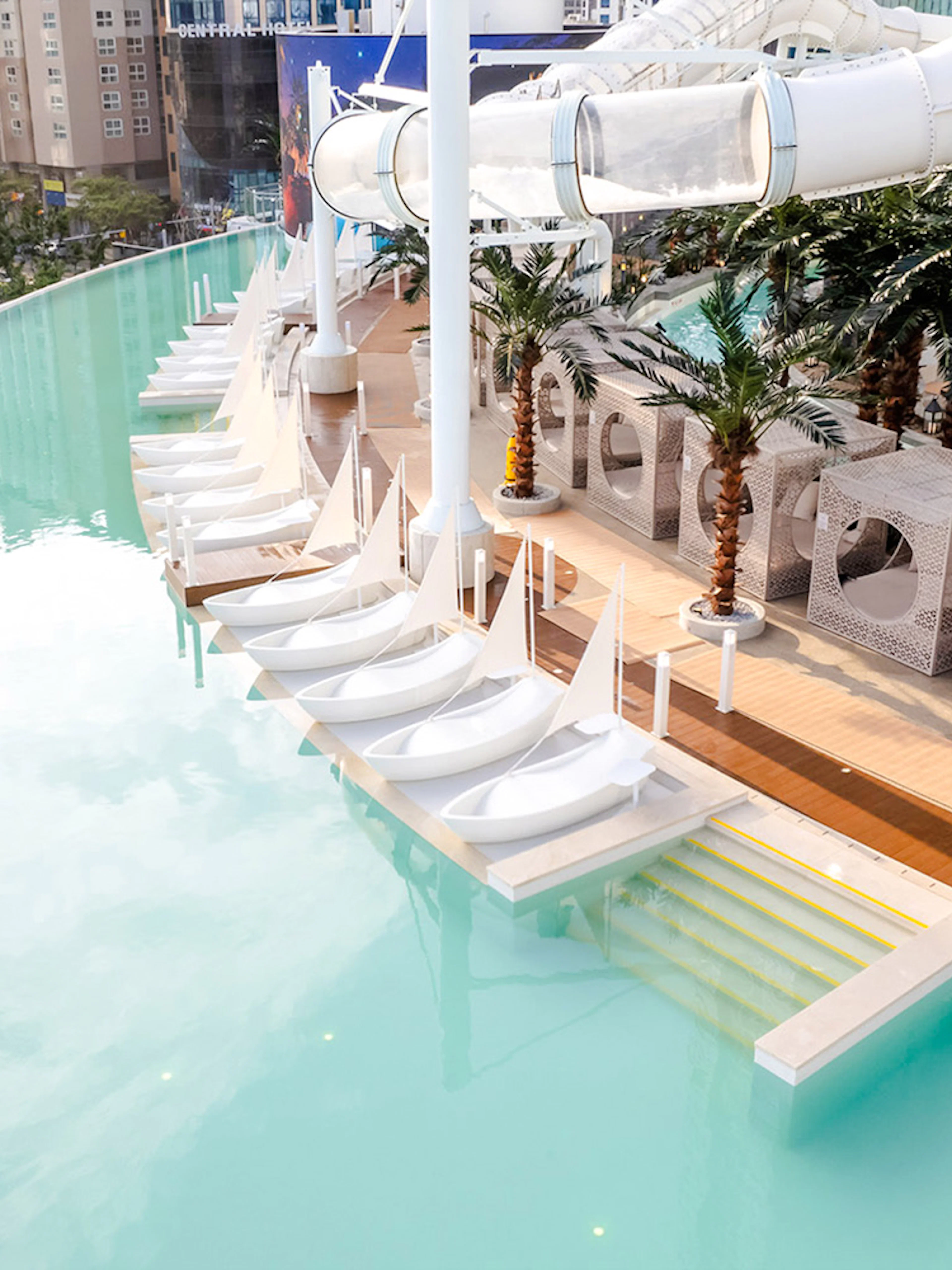 Rooftop infinity pool with sail-shaped loungers, cabanas, and waterslide at Club D Oasis.