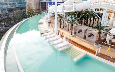 Rooftop infinity pool with sail-shaped loungers, cabanas, and waterslide at Club D Oasis.