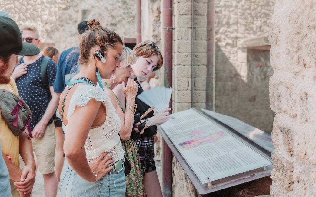 Visitors reading information plaques on a Pompeii VIP small group tour.
