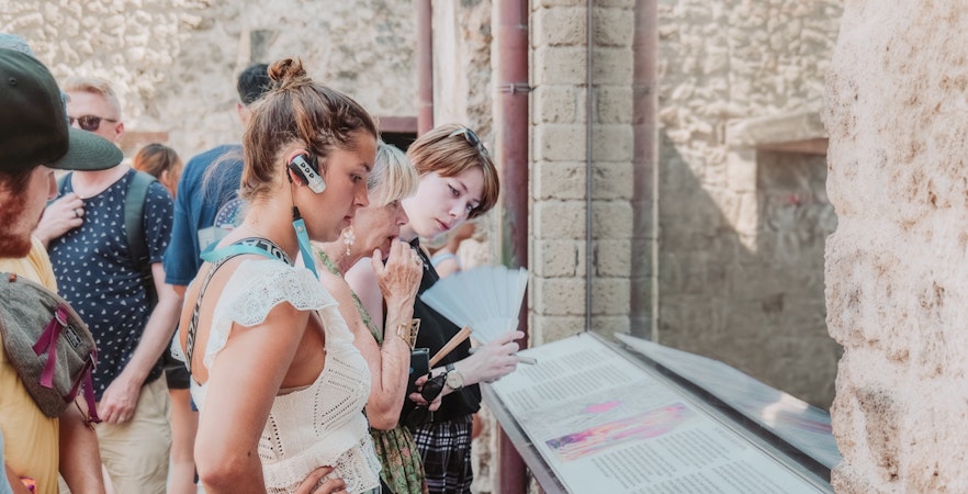 Visitors reading information plaques on a Pompeii VIP small group tour.