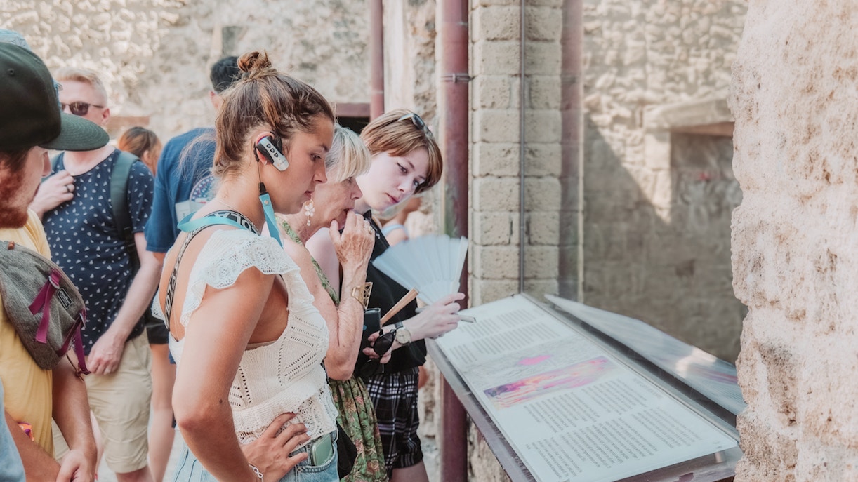 Visitors reading information plaques on a Pompeii VIP small group tour.