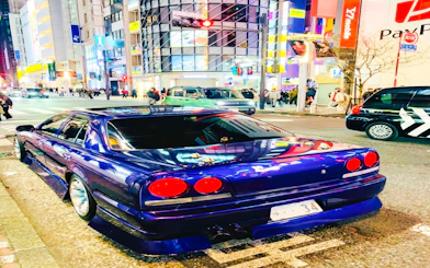 Super car parked on a busy street in Tokyo at night.