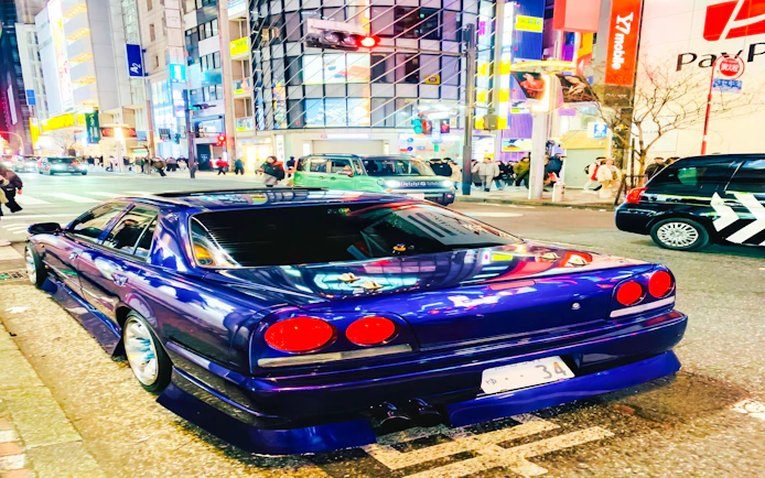 Super car parked on a busy street in Tokyo at night.