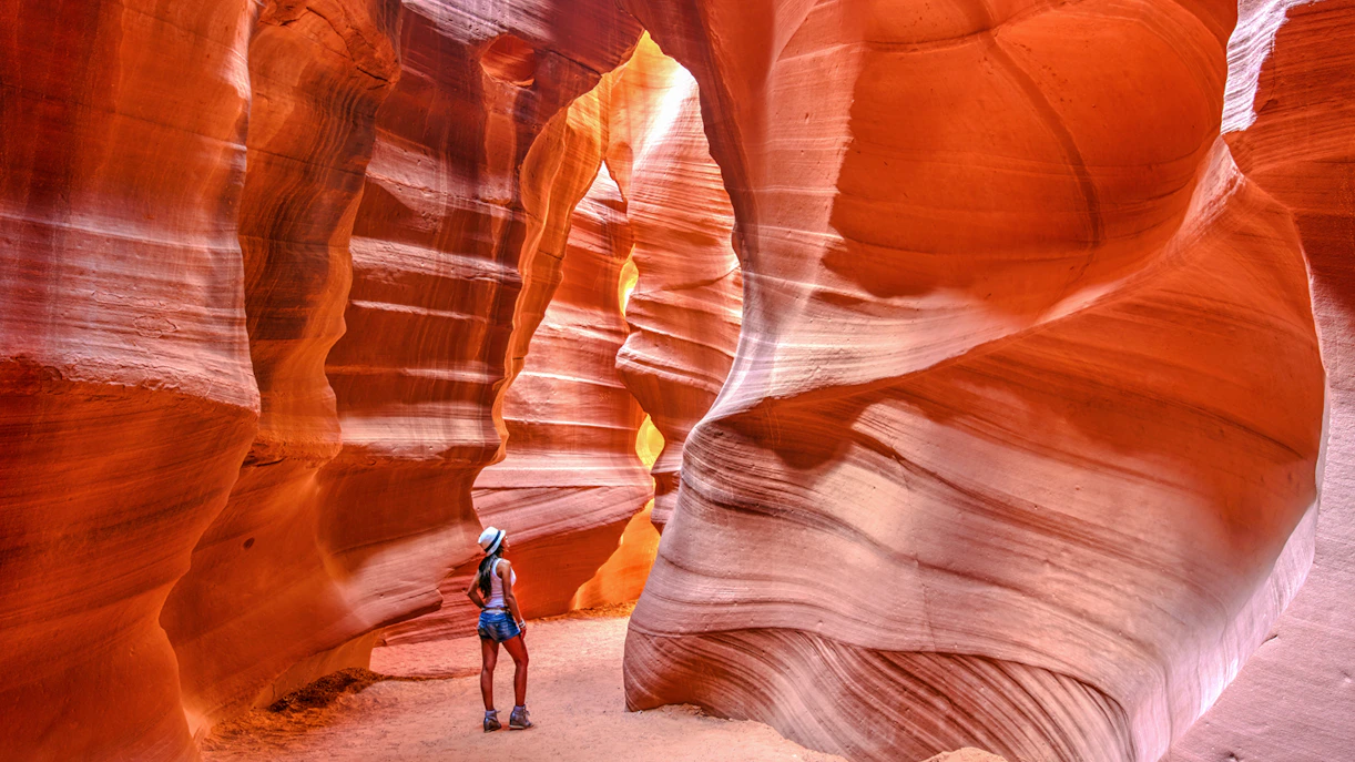 Visitor exploring the narrow sandstone walls of Upper Antelope Canyon, Arizona.