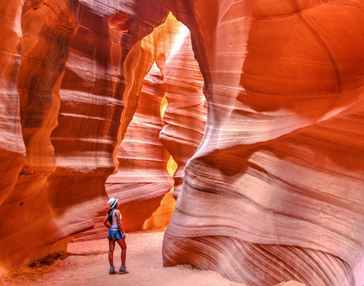 Visitor exploring the narrow sandstone walls of Upper Antelope Canyon, Arizona.