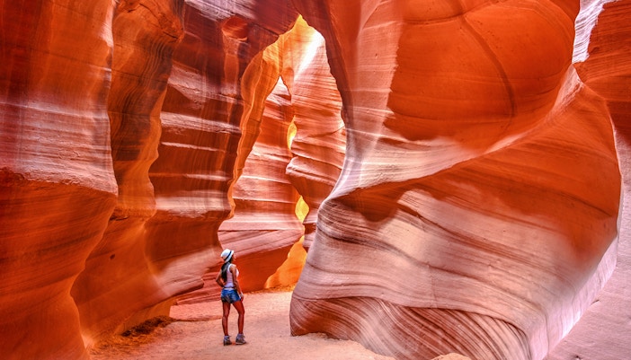 Visitor exploring the narrow sandstone walls of Upper Antelope Canyon, Arizona.