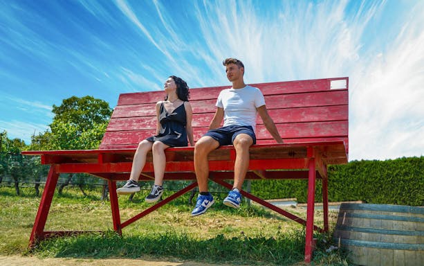 Couple sitting on a giant red bench in Langhe during a Vespa tour.