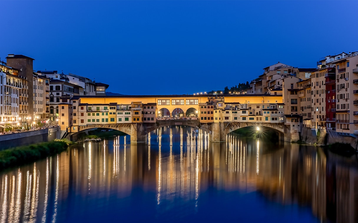 Ponte Vecchio illuminated at night over the Arno River in Florence, Italy.