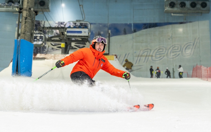 Skier in orange jacket on indoor slope at Ski Dubai.