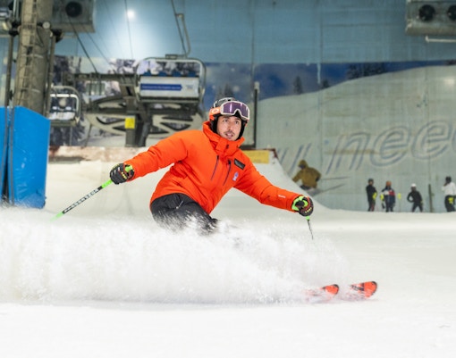 Skier in orange jacket on indoor slope at Ski Dubai.