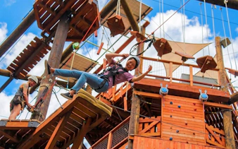 Participant on an adventure course with obstacles, climbing wall, and freefall.