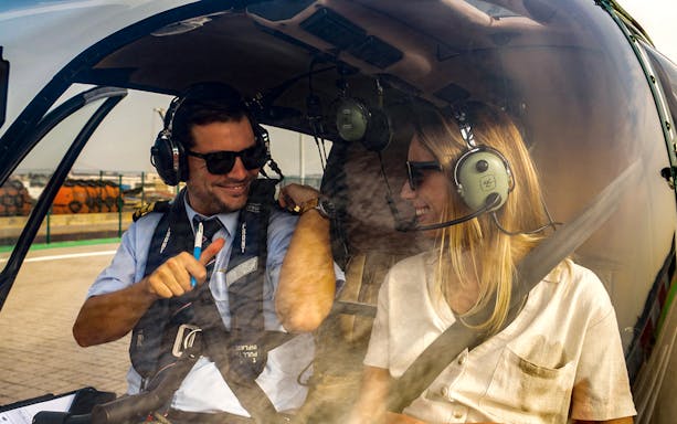 Pilot and passenger in helicopter cockpit during Lisbon coastline flight.