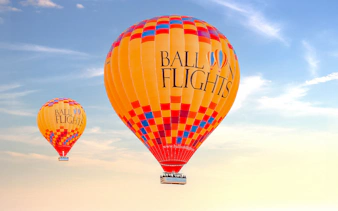 Hot air balloons in flight against a clear sky, part of a tour with hotel transfers and activities.