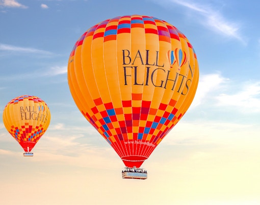 Hot air balloons in flight against a clear sky, part of a tour with hotel transfers and activities.