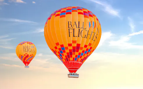 Hot air balloons in flight against a clear sky, part of a tour with hotel transfers and activities.