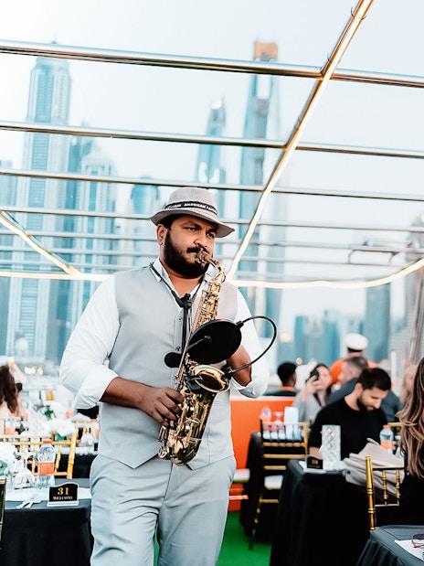 Saxophonist performing on a Dubai Marina sunset cruise with buffet dinner.