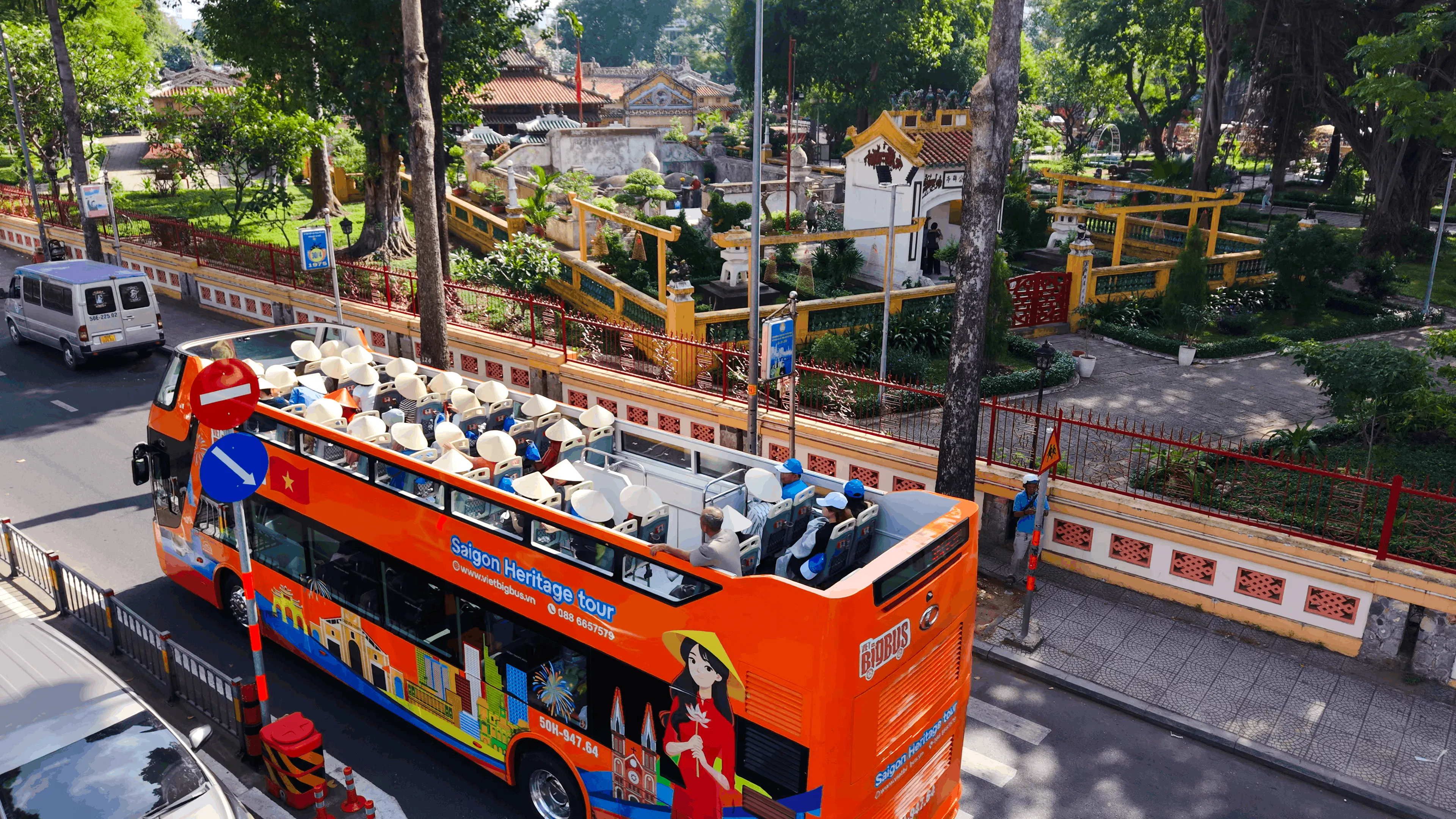 Open-top bus on Saigon Heritage tour passing historic site in Ho Chi Minh City.
