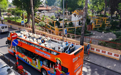 Open-top bus on Saigon Heritage tour passing historic site in Ho Chi Minh City.