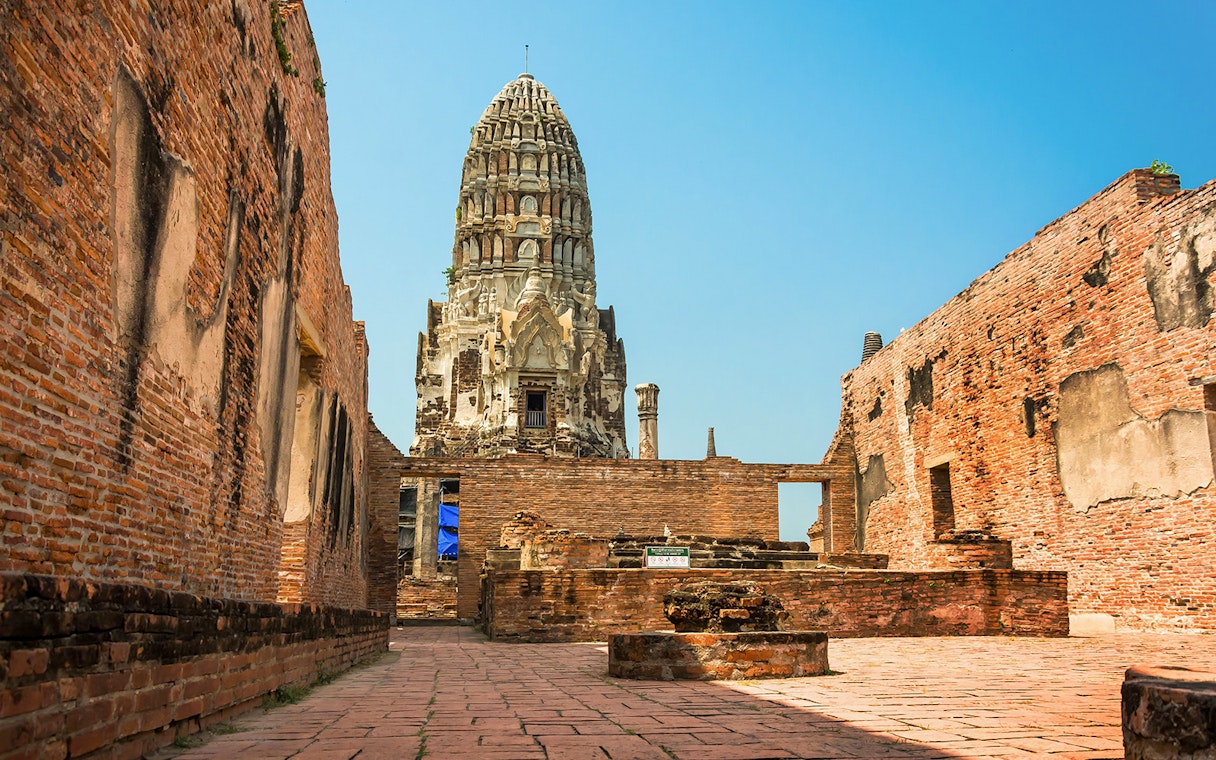 Wat Ratchaburana prang viewed between ancient brick walls in Ayutthaya.