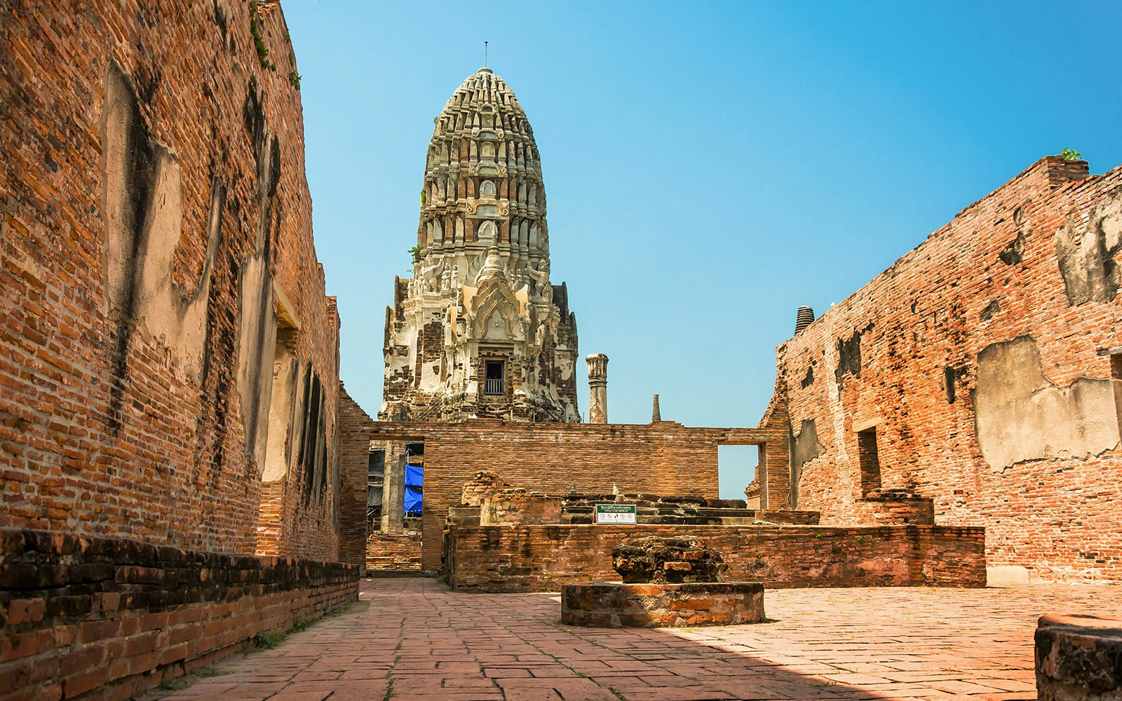 Wat Ratchaburana prang viewed between ancient brick walls in Ayutthaya.