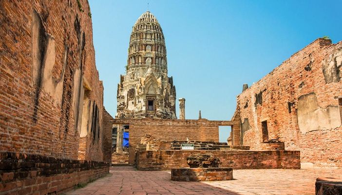Wat Ratchaburana prang viewed between ancient brick walls in Ayutthaya.
