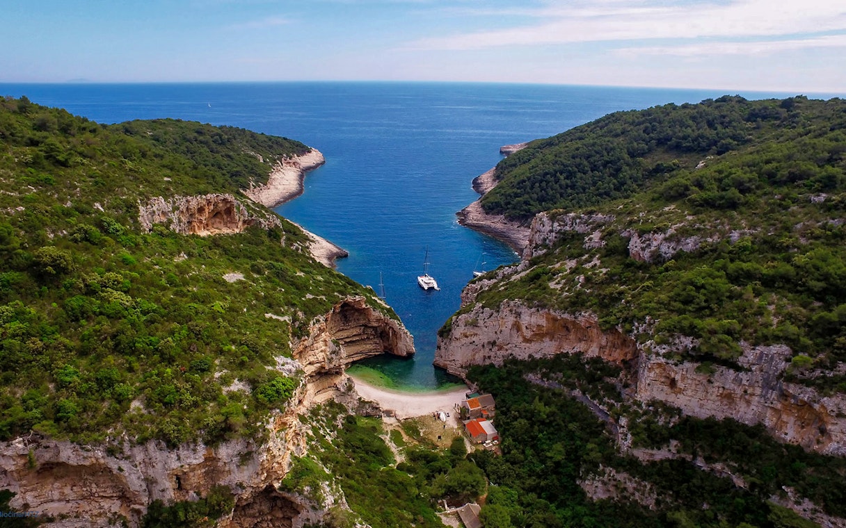 Aerial view of secluded cove with yachts, part of 5 Islands Hopping Tour with Blue Cave visit.