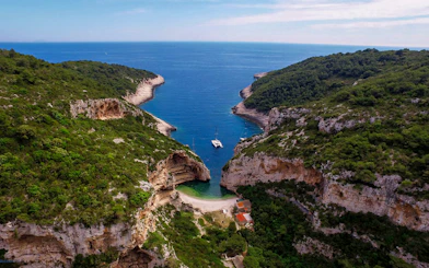 Aerial view of secluded cove with yachts, part of 5 Islands Hopping Tour with Blue Cave visit.
