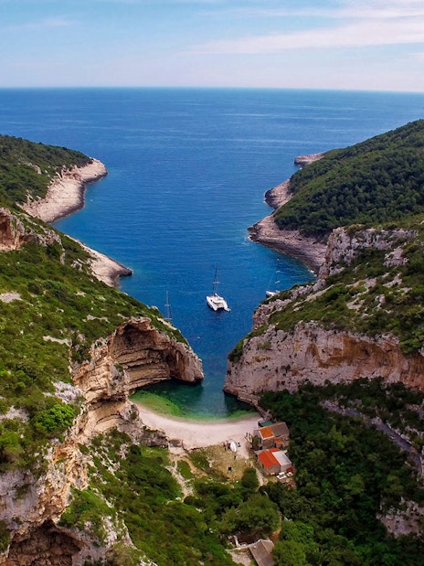 Aerial view of secluded cove with yachts, part of 5 Islands Hopping Tour with Blue Cave visit.