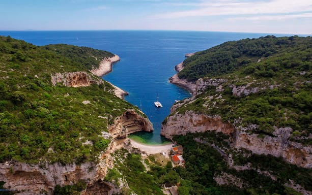 Aerial view of secluded cove with yachts, part of 5 Islands Hopping Tour with Blue Cave visit.
