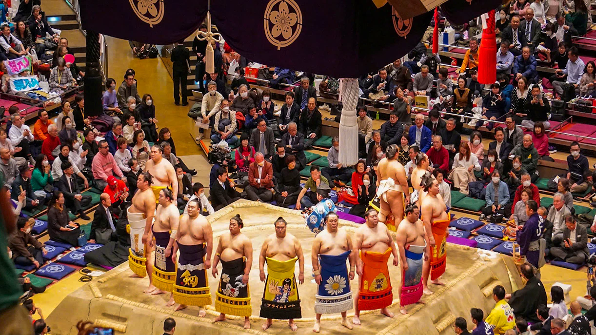 Sumo wrestlers in a Tokyo arena during an English-guided tournament tour.