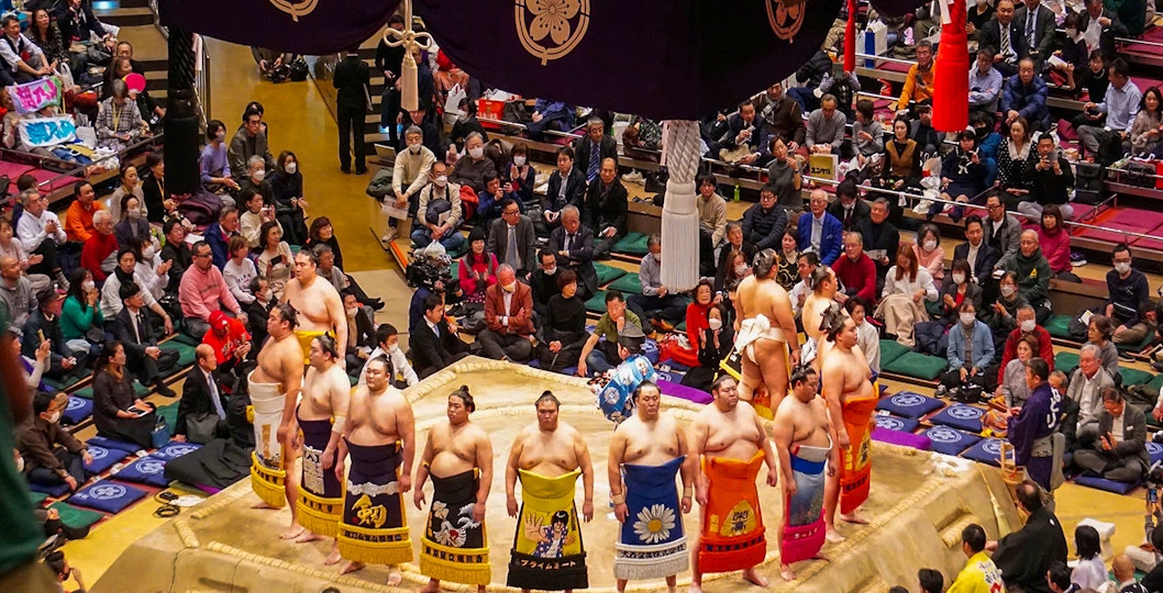 Sumo wrestlers in a Tokyo arena during an English-guided tournament tour.