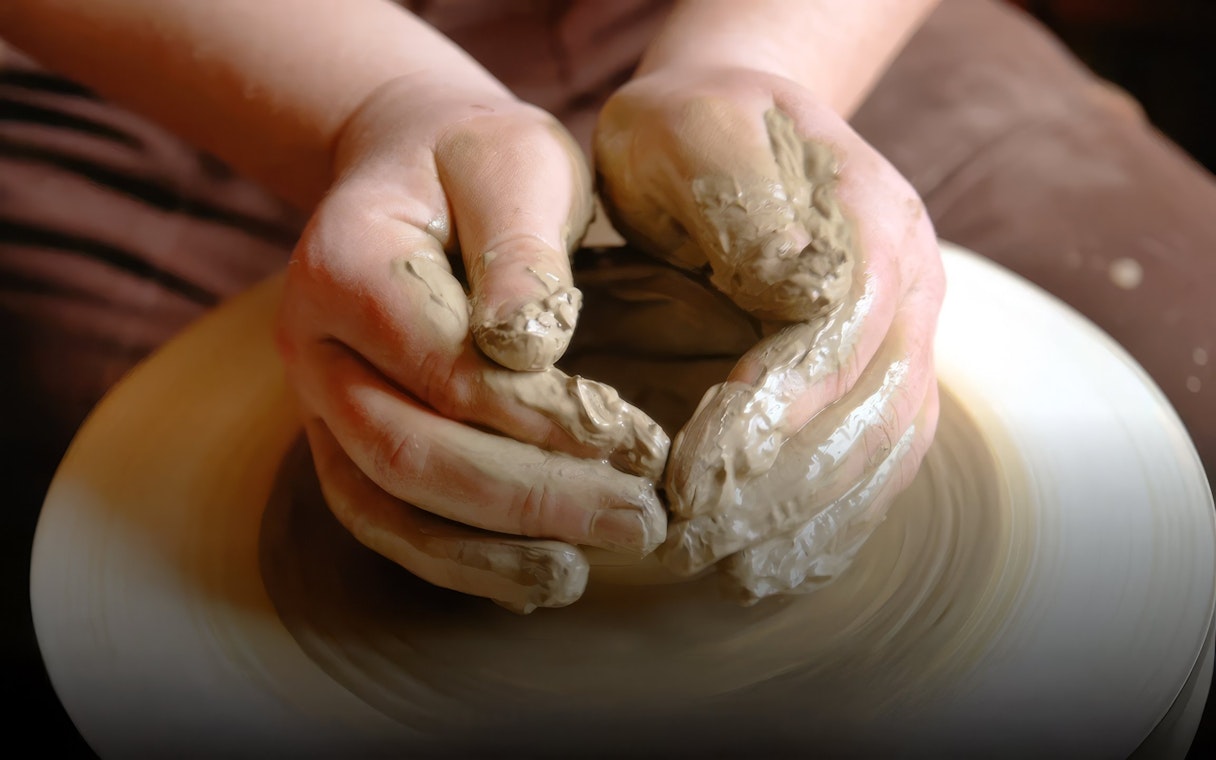 Hands shaping clay on a pottery wheel in Avanos class.