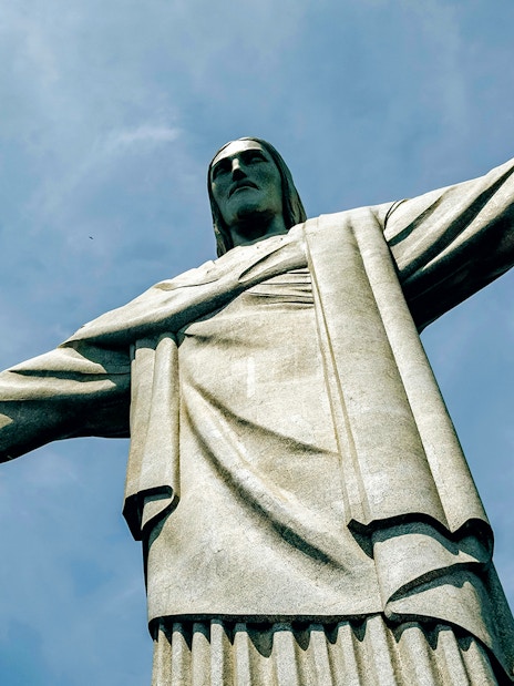 Christ the Redeemer statue with outstretched arms against blue sky, Rio de Janeiro, Brazil.