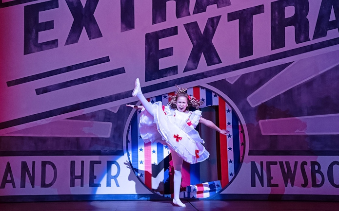 Performer in a white costume dancing on stage during a "Gypsy" musical scene.