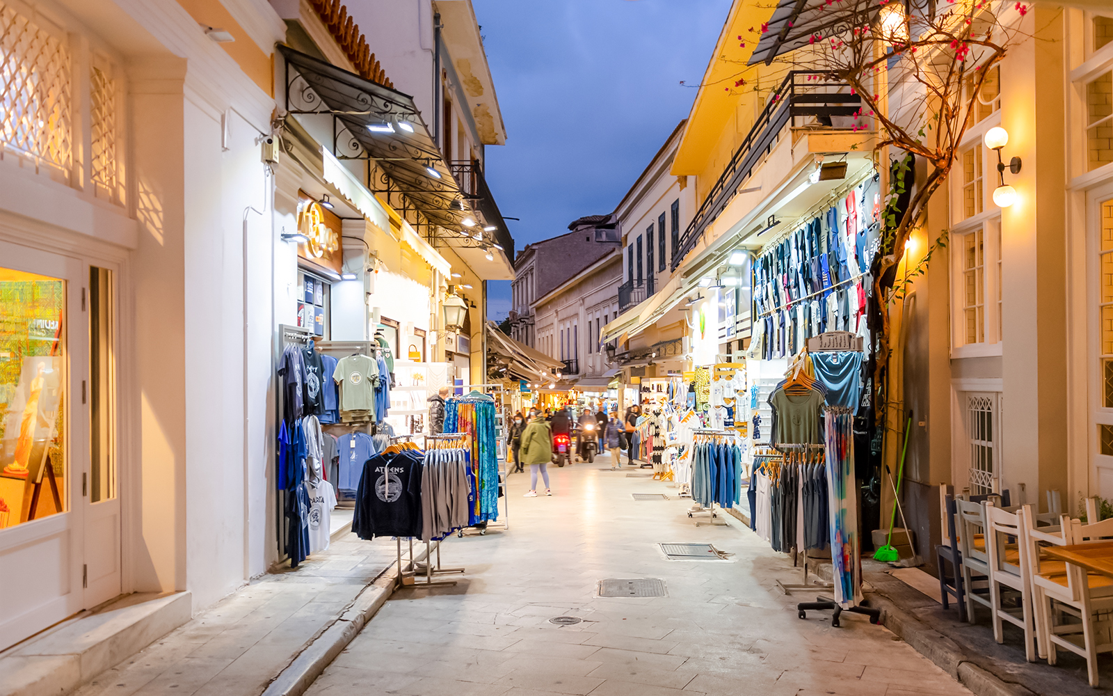 Shops and pedestrians on Adrianou Street in Athens at dusk.