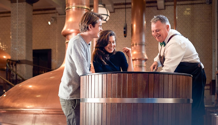 Visitors exploring Heineken brewery in Amsterdam with drinks in hand.