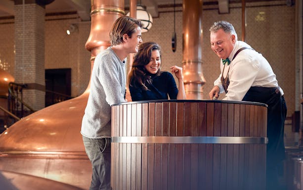 Visitors interacting with a guide inside the Heineken brewery in Amsterdam.