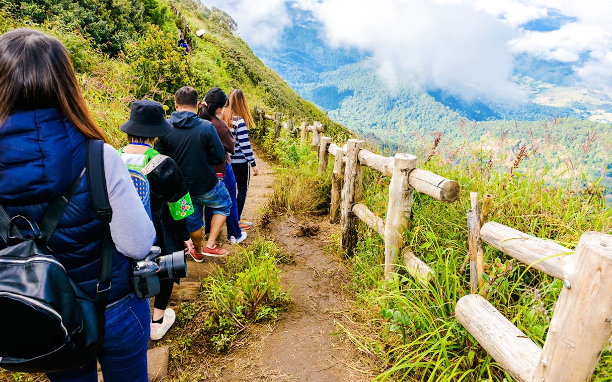 Group trekking on Kew Mae Parn trail, Inthanon National Park, Thailand at sunrise.