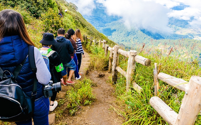 Group trekking on Kew Mae Parn trail, Inthanon National Park, Thailand at sunrise.