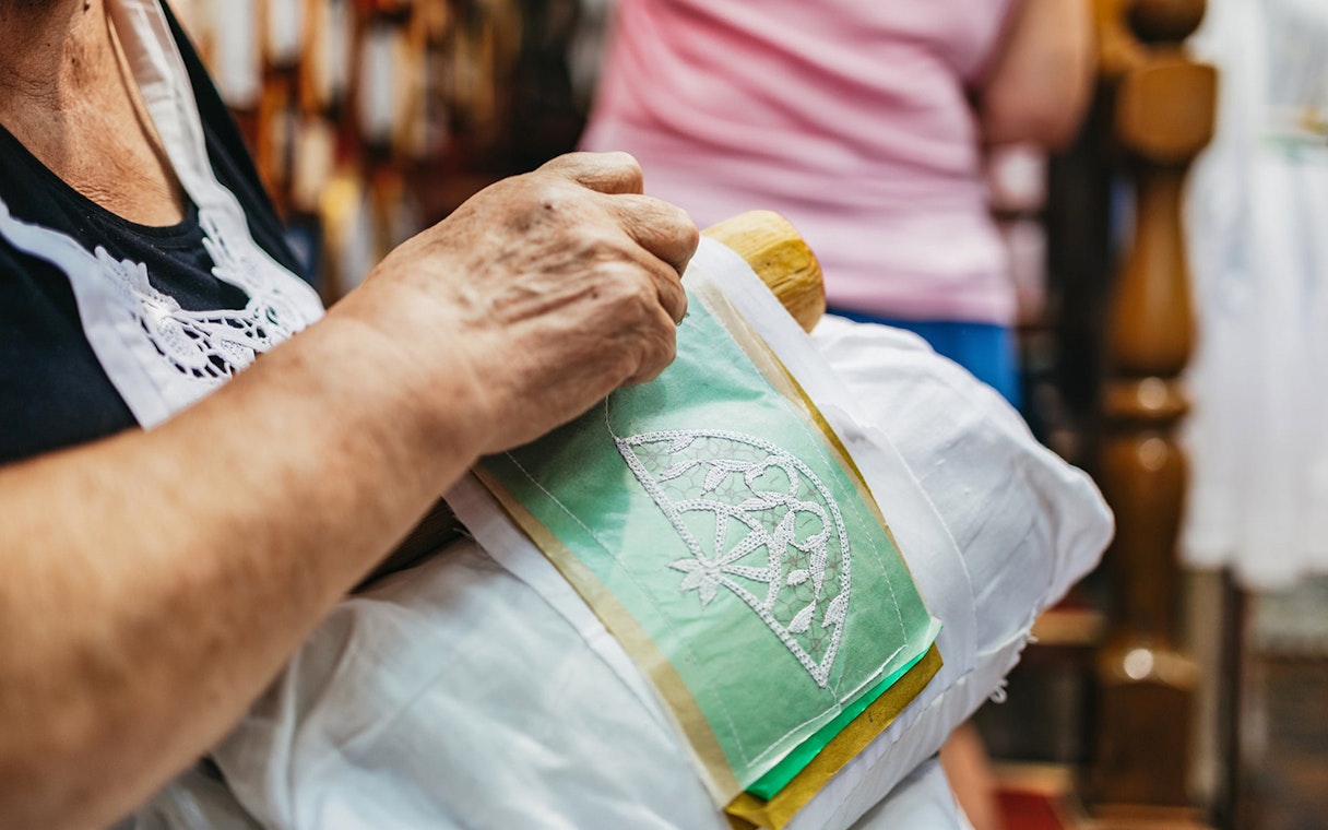Lace making demonstration in Burano, Italy, showing intricate needlework on fabric.
