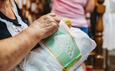 Lace making demonstration in Burano, Italy, showing intricate needlework on fabric.