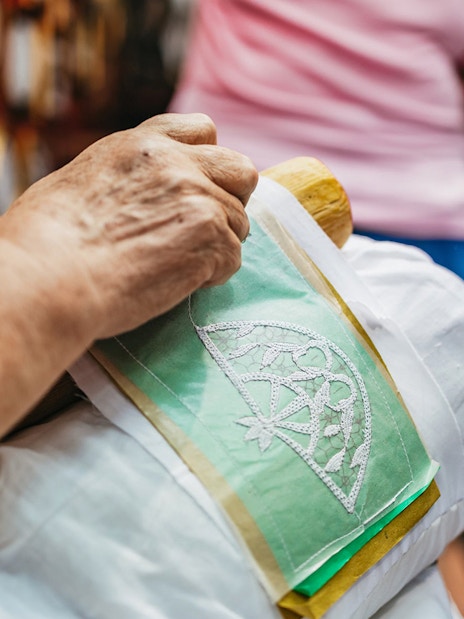 Lace making demonstration in Burano, Italy, showing intricate needlework on fabric.