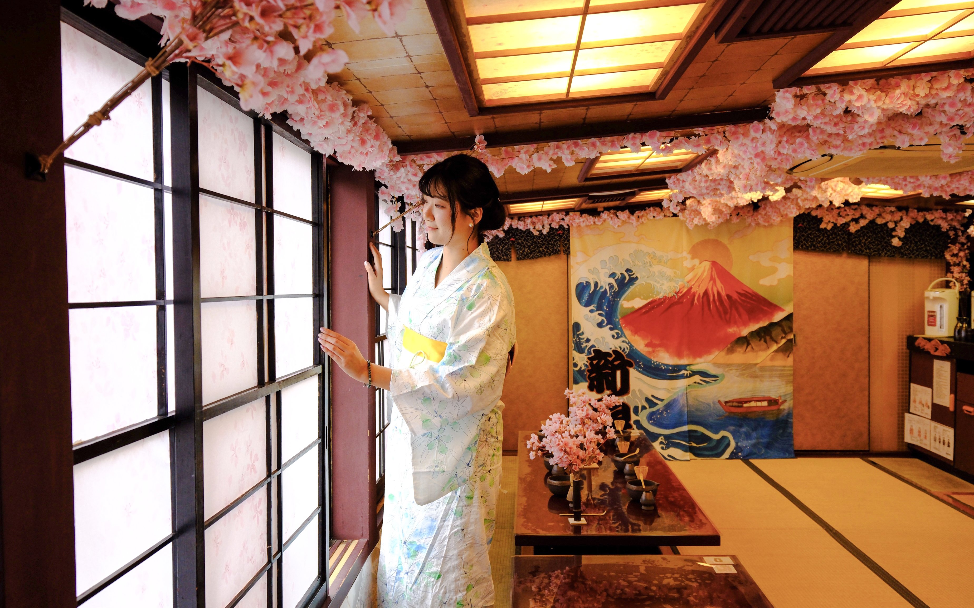 Woman in kimono at Tokyo tea ceremony room with cherry blossoms and Mount Fuji artwork.