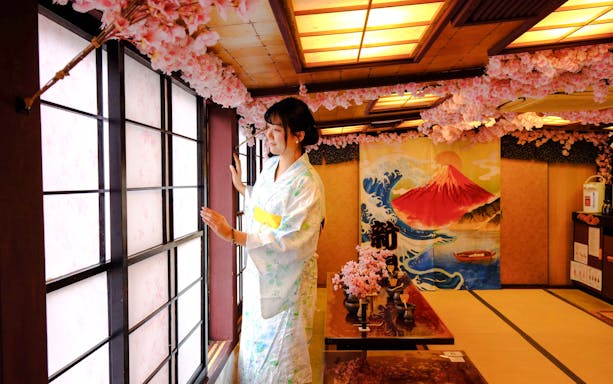 Woman in kimono at Tokyo tea ceremony room with cherry blossoms and Mount Fuji artwork.