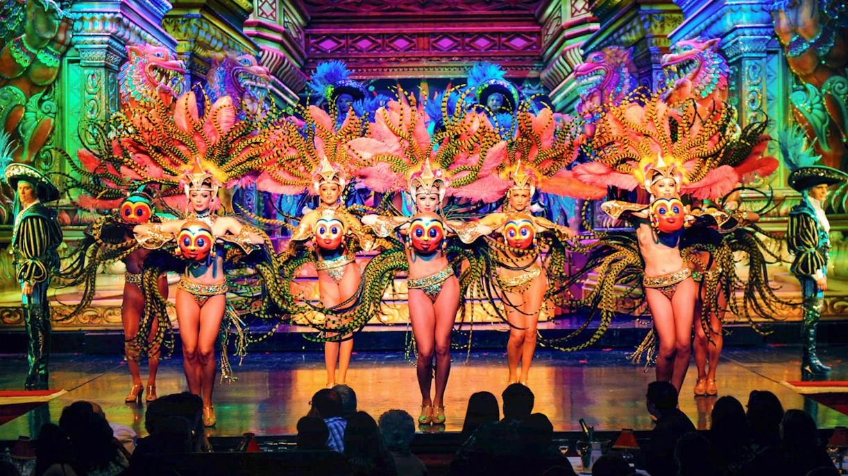 Moulin Rouge Paris dancers performing on stage with vibrant costumes and champagne on table.