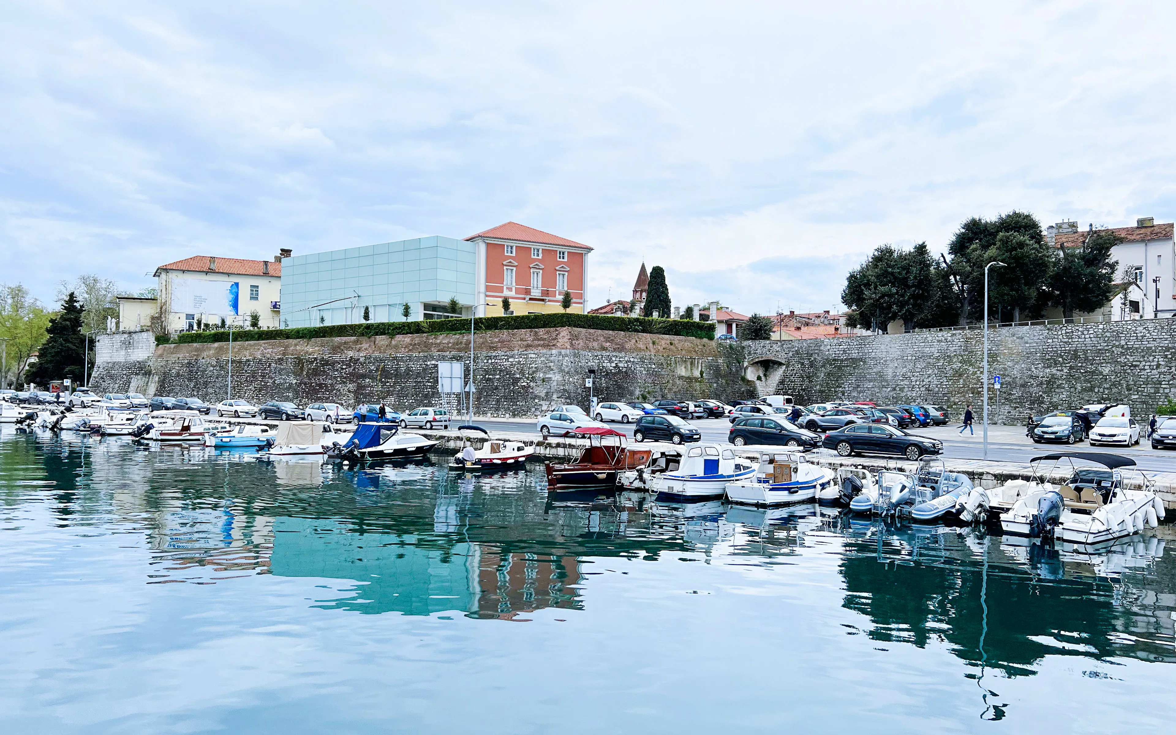 Boats docked at Jazine port with historic buildings in Zadar, Croatia.