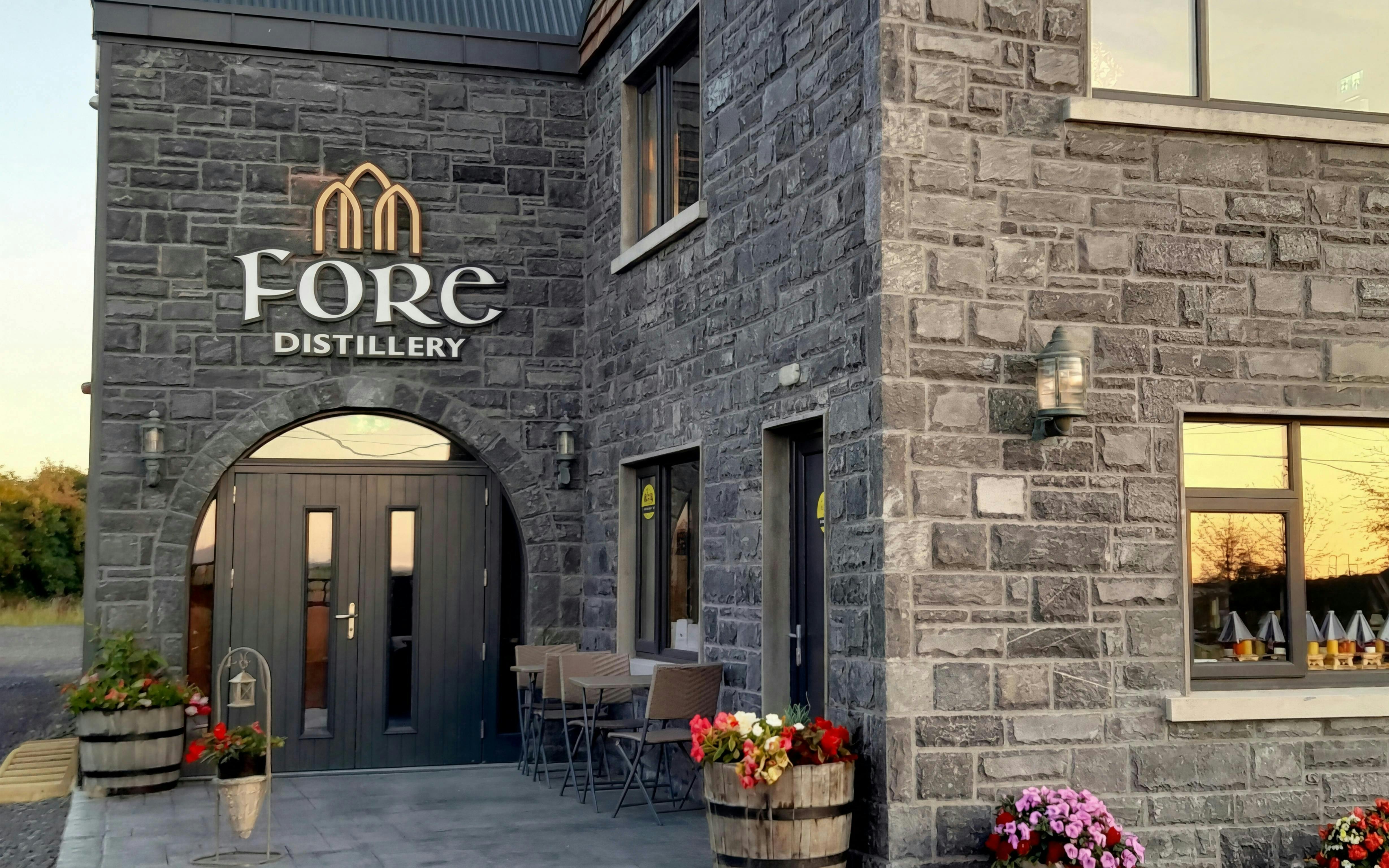 Fore Distillery entrance with stone facade and flower barrels.