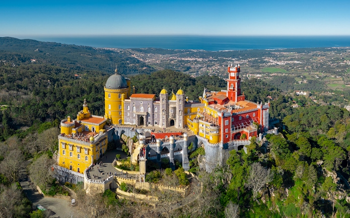 Aerial view of Pena Palace and Park in Sintra, Portugal, surrounded by lush greenery.