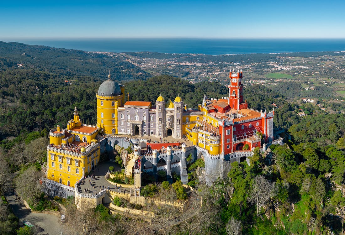 Aerial view of Pena Palace and Park in Sintra, Portugal, showcasing vibrant architecture and lush greenery.