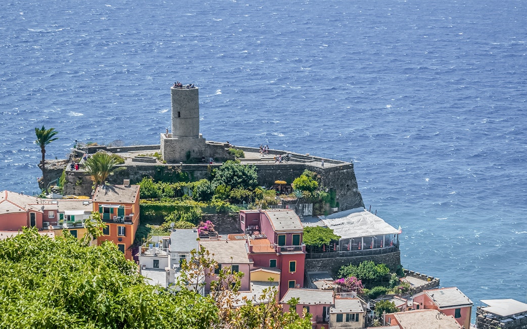 Doria Castle overlooking the sea in Vernazza, Italy, with colorful buildings below.